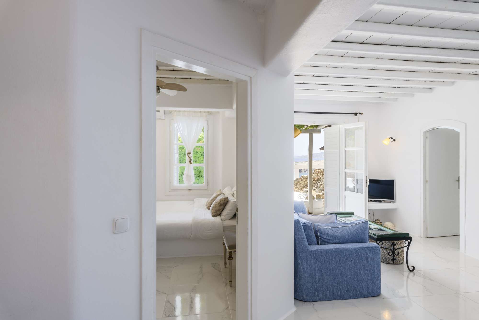 Ein modernes Interieur mit einem Bett, einem blauen Sofa, einem Fernseher und einer Steinwand.