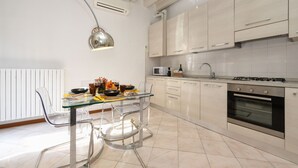 A modern kitchen with a glass dining table, clear chairs, a microwave, a gas stove, and white cabinets. - DesenzanoLoft Le Petit Bijou - Restyling 2025 - Downtown (Desenzano del Garda)