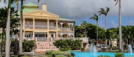 A hotel with a large pool, palm trees, and a well-maintained lawn.
