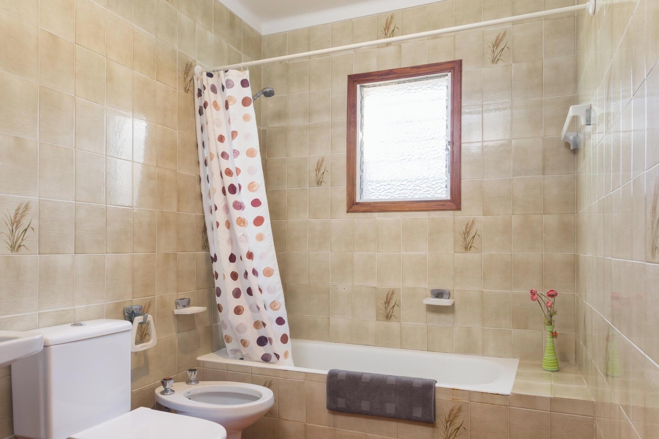 Un baño con inodoro, bidé, bañera y cortina de ducha.
