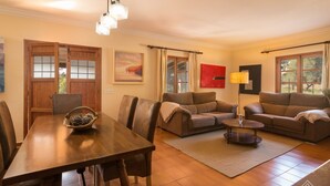 A living room with a wooden dining table, two sofas, a coffee table, and a floor lamp. - Casa Tonina - Beautiful villa with pool and garden in Pollença (Pollença)