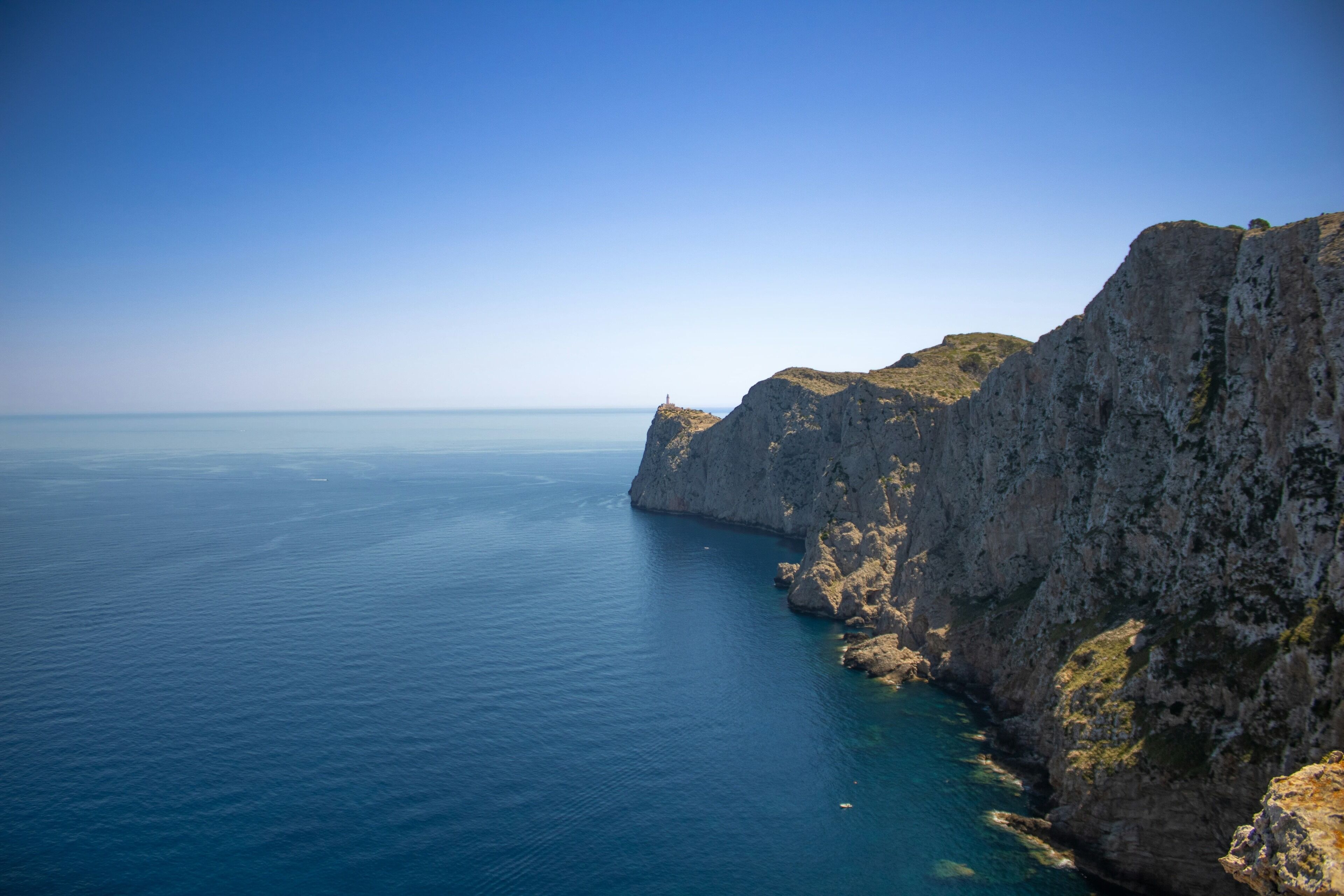 A coastal landscape with a rocky cliff and calm sea.