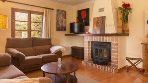 A cozy living room with a fireplace, a sofa, a coffee table, and artwork on the walls. - Casa Tonina - Beautiful villa with pool and garden in Pollença (Pollença)