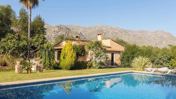 A pool with a mountain backdrop, surrounded by lush greenery and a traditional house. - Casa Tonina - Beautiful villa with pool and garden in Pollença (Pollença)