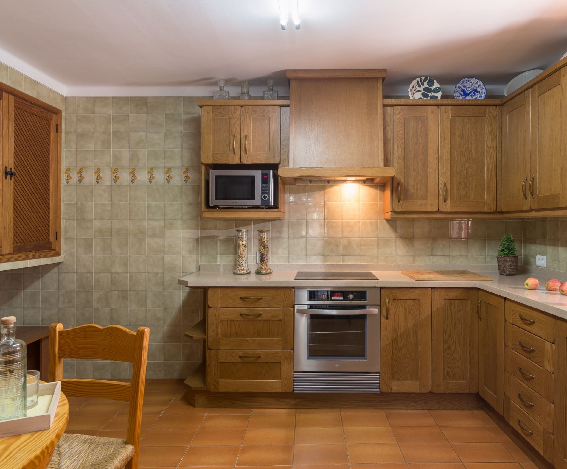 A kitchen with wooden cabinets, a microwave, an oven, and a sink.