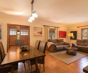 A living room with a wooden dining table, two sofas, a coffee table, and a floor lamp. - Casa Tonina - Beautiful villa with pool and garden in Pollença (Pollença)