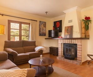 A cozy living room with a fireplace, a sofa, a coffee table, and artwork on the walls. - Casa Tonina - Beautiful villa with pool and garden in Pollença (Pollença)