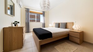 Une chambre à coucher moderne avec un lit en bois, des tables de chevet, un miroir et une vue sur l’extérieur.