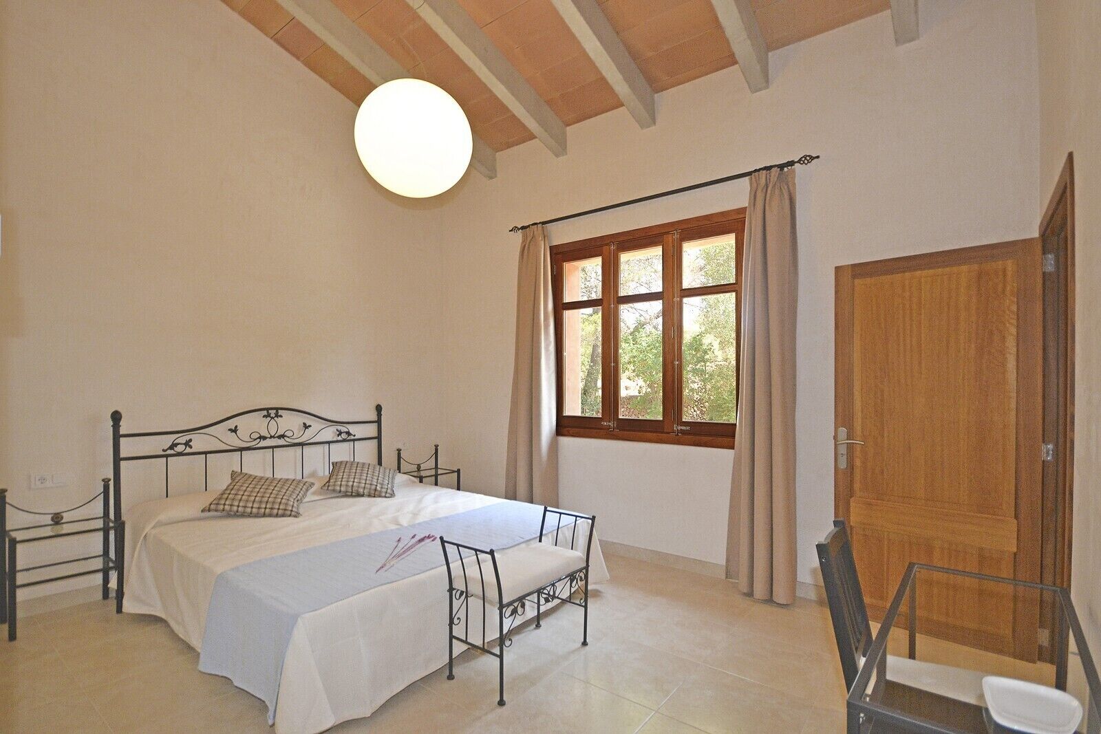 Une chambre à coucher avec un lit, une chaise, une fenêtre avec des rideaux et une porte.
