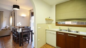 A compact kitchen with a dishwasher, wooden cabinets, and a dining area with a table and chairs. - Holiday rental semidetached with swimming pool in Begur, Centre (Begur)