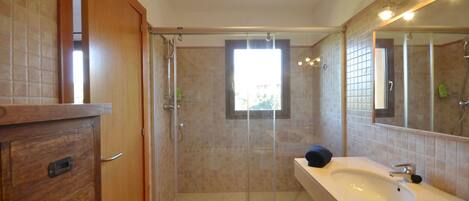 Un baño con ducha de vidrio, un mueble de madera y un espejo grande.