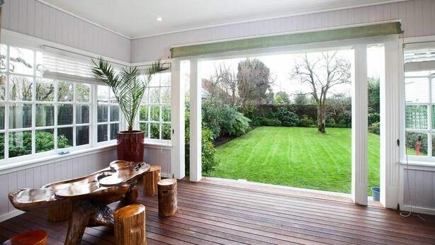 A spacious room with a large window overlooking a well-maintained garden. - 200 Riccarton Holiday House (Christchurch)