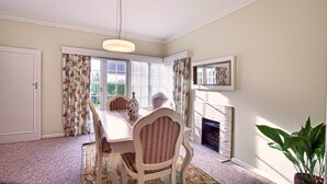 A dining room with a table, chairs, a chandelier, a fireplace, and a large window with curtains. - 200 Riccarton Holiday House (Christchurch)
