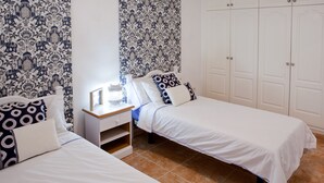 Een slaapkamer met twee bedden, een nachtkastje en een kledingkast.