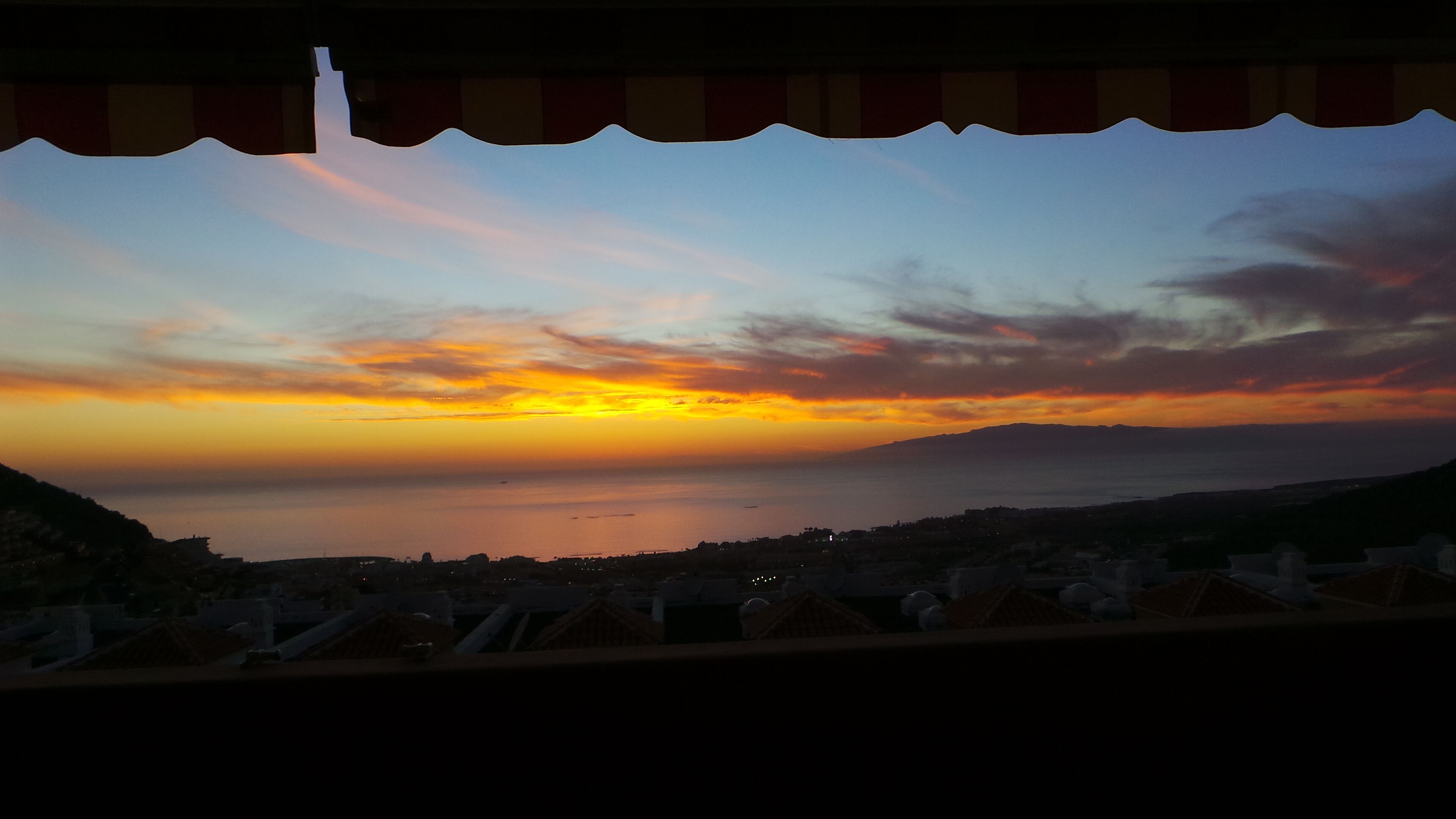 Vista al tramonto sulla costa da un balcone con ringhiera.