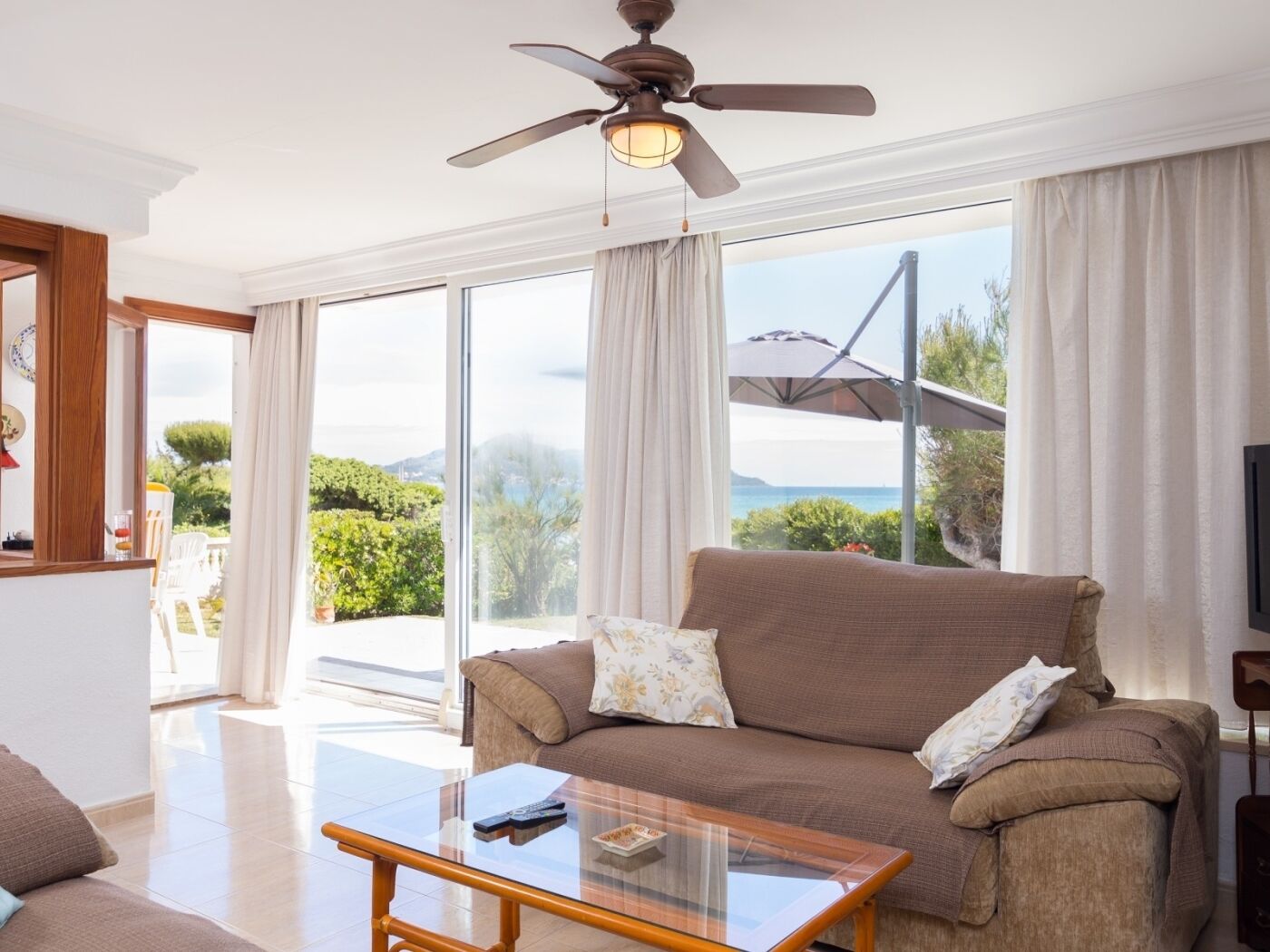 A spacious living room with a large window offering a view of the sea and greenery.