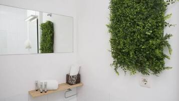 Un baño con espejo, repisas con artículos de aseo y un jardín vertical.