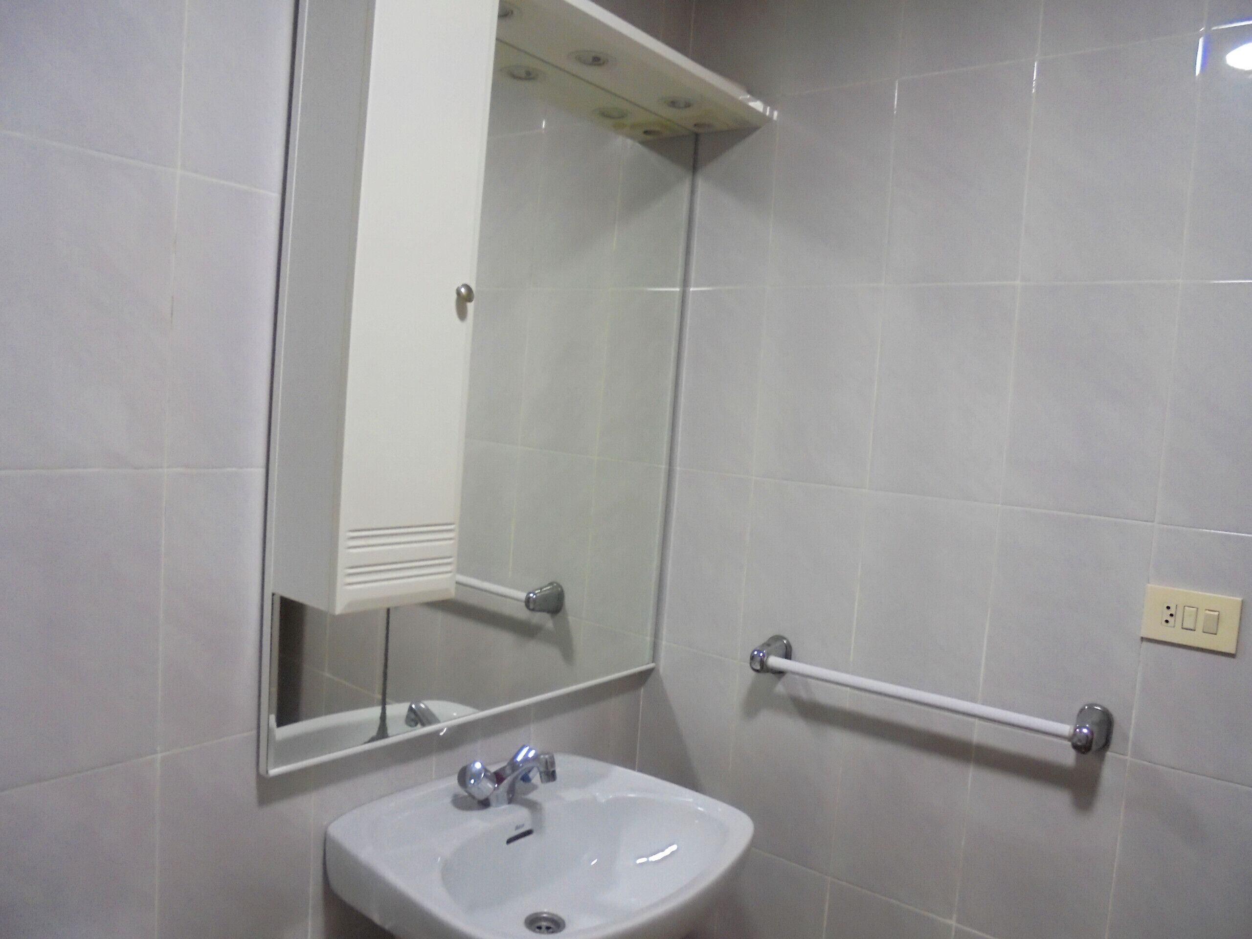 Ein Badezimmer mit einem weißen Waschbecken, einem Spiegel und einem Handtuchhalter.