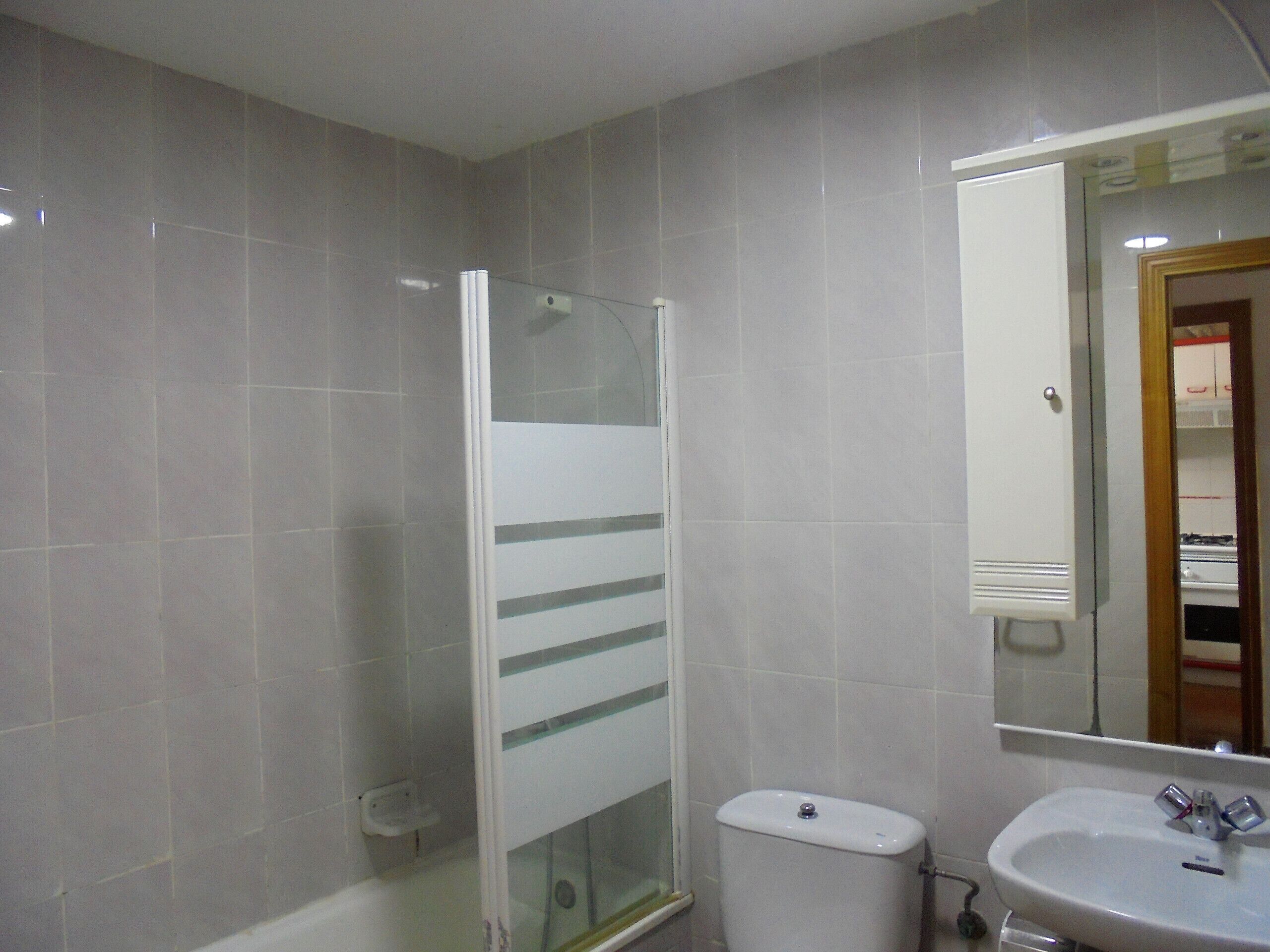 Une salle de bain avec une douche à parois de verre, des toilettes et un lavabo avec un miroir au-dessus.