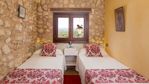 A room with two beds, a stone wall, a window with a view, and an air conditioning unit. - Casa del Sol - Beautiful town house with pool and views of the countryside (Búger)
