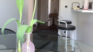A dining area with a glass table, a pink vase with a tulip, and a view into a room with a mirror and a small table. - Da Vinci Verona, elegant apartment in Borgo Trento, 120 m², parking space (Verona)