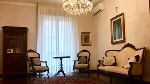 A room with a chandelier, two armchairs, a sofa, a table, and a large window with curtains. - Da Vinci Verona, elegant apartment in Borgo Trento, 120 m², parking space (Verona)