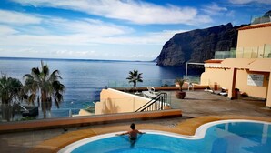 A swimming pool with a view of the ocean and a mountain in the background.