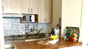 A kitchen with wooden cabinets, a microwave, a sink, and a dining area with a wooden table and white chairs.
