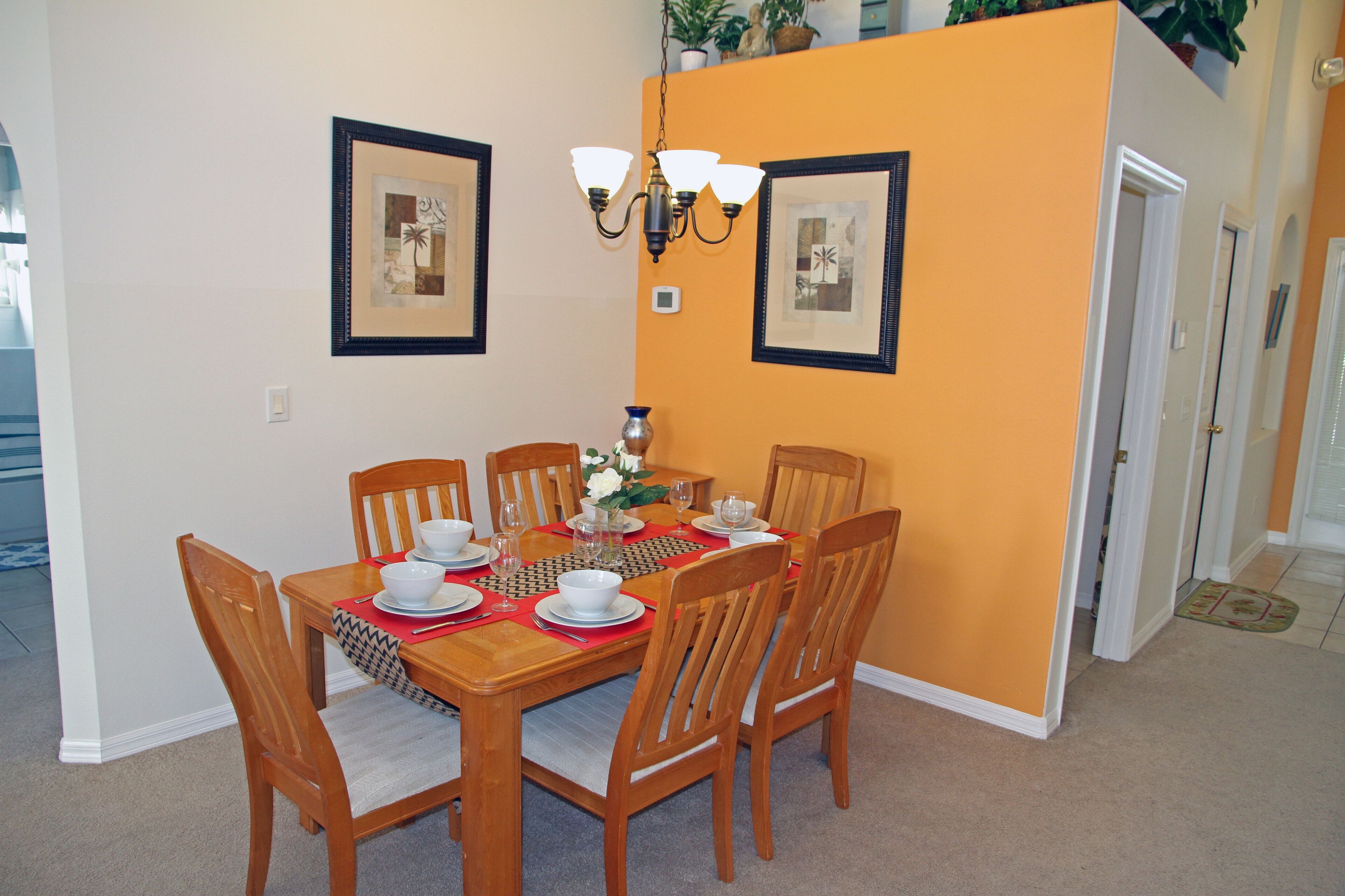 A dining area with a wooden table set for six, surrounded by six chairs.