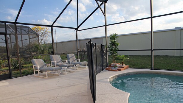 Un espace piscine extérieur doté d’un patio couvert, de chaises longues et d’un petit jardin.