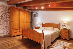 Une chambre à coucher avec un lit en bois, des tables de chevet, une armoire et un mur décoré d’un motif imitant la pierre.