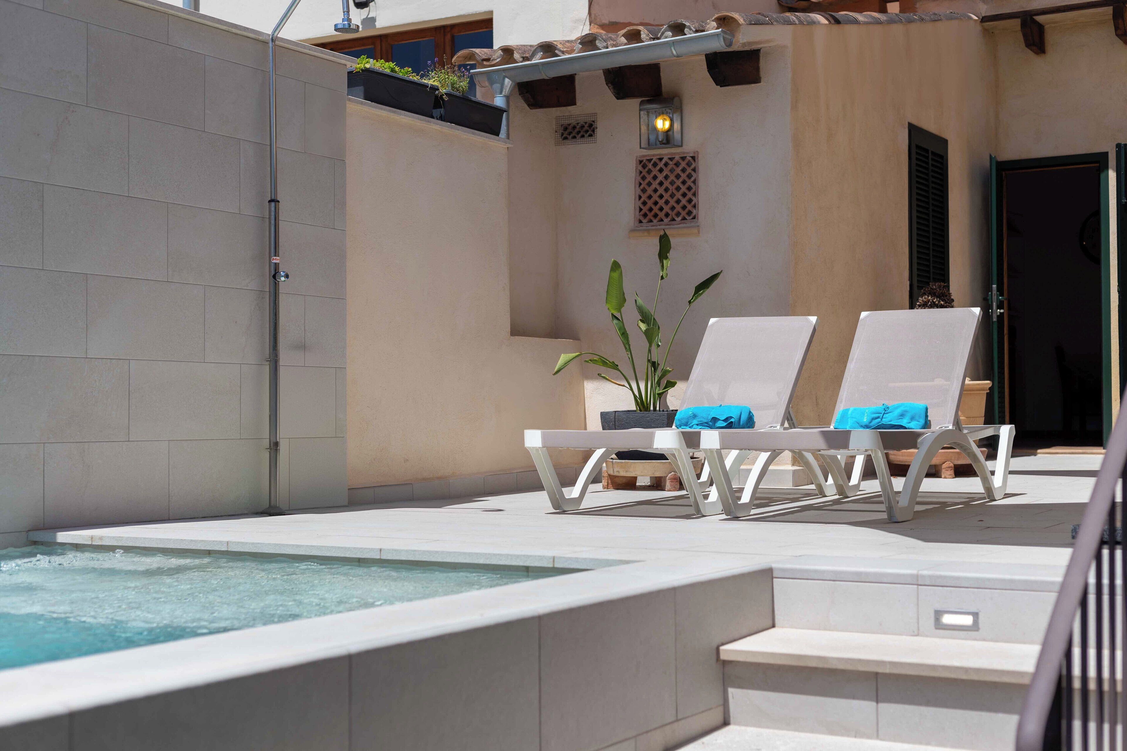 A spa area with a hot tub, two lounge chairs, and a potted plant.