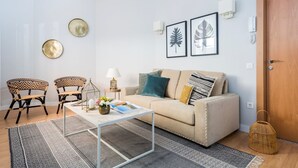 A living room with a beige sofa, two patterned chairs, a coffee table, and a door. - Genteel Home Trinidad Grund H (Málaga)