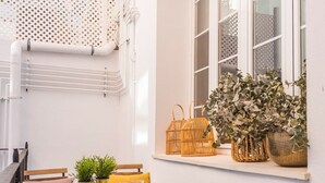 A small outdoor seating area with a table, chairs, and a window with potted plants. - Genteel Home Trinidad Grund H (Málaga)