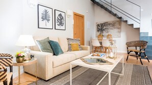 A modern living room with a sofa, coffee table, and chairs, a staircase, and artwork on the walls. - Genteel Home Trinidad Grund H (Málaga)