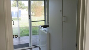 A small kitchen with a built-in dishwasher, a window with a view of a garden, and a door leading to an outdoor area.