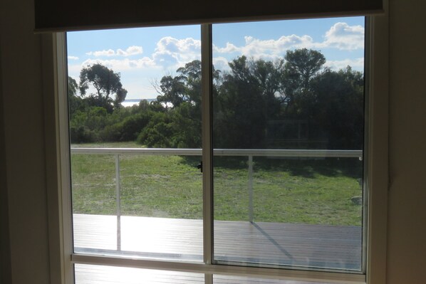 A room with a large window overlooking a grassy deck and trees.