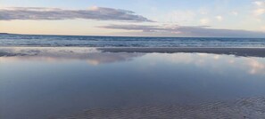 Una playa con agua tranquila que refleja el cielo.