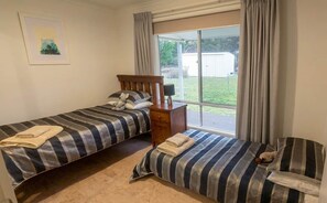 Une chambre avec deux lits, une table de chevet et une fenêtre avec des rideaux.
