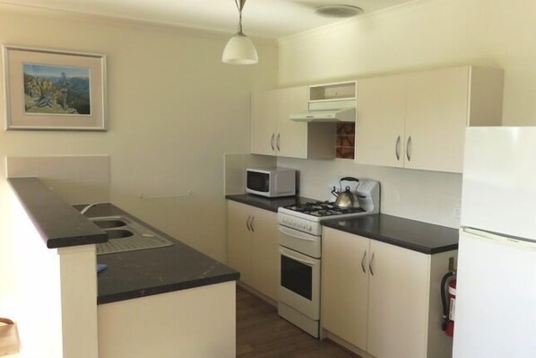 A compact kitchen with a microwave, stove, and refrigerator.