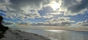 Una platja amb cel blau i reflexos de sol a l'aigua.