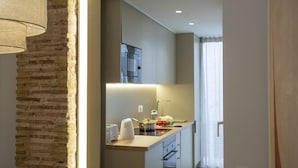 A modern kitchen with a brick accent wall, a built-in oven, and a countertop with a kettle, toaster, and vegetables.