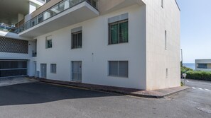 Un bâtiment moderne à la façade plate, doté de nombreuses fenêtres et d’une entrée protégée par un portail.