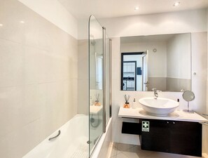 Enjoy a refreshing shower in this sleek bathroom with a glass-enclosed shower area and a spacious vanity.