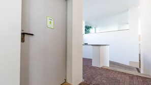 Eine weiße Tür mit einem LIXO-Schild, eine weiße Säule und ein Backsteinboden.
