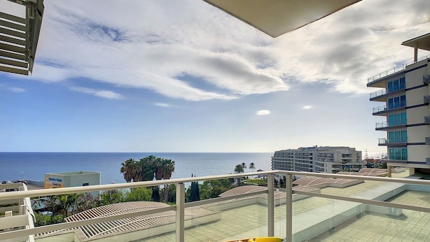 Een balkon met een ontbijtset, met uitzicht op de kust.