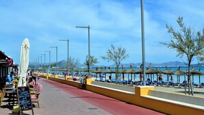 A seaside promenade with outdoor seating, umbrellas, and beach chairs. - Casa Alba 159 cosy holiday home with garden, terrace in residential area, barbecue and WiFi (Can Picafort)