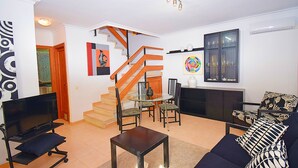 A modern living room with a TV, sofa, and dining area. - Casa Alba 159 cosy holiday home with garden, terrace in residential area, barbecue and WiFi (Can Picafort)