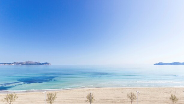 A beach with clear blue water and distant mountains. - Casa Alba 159 cosy holiday home with garden, terrace in residential area, barbecue and WiFi (Can Picafort)