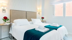 Een hotelkamer met twee bedden, een nachtkastje, een lamp en een raam met uitzicht.